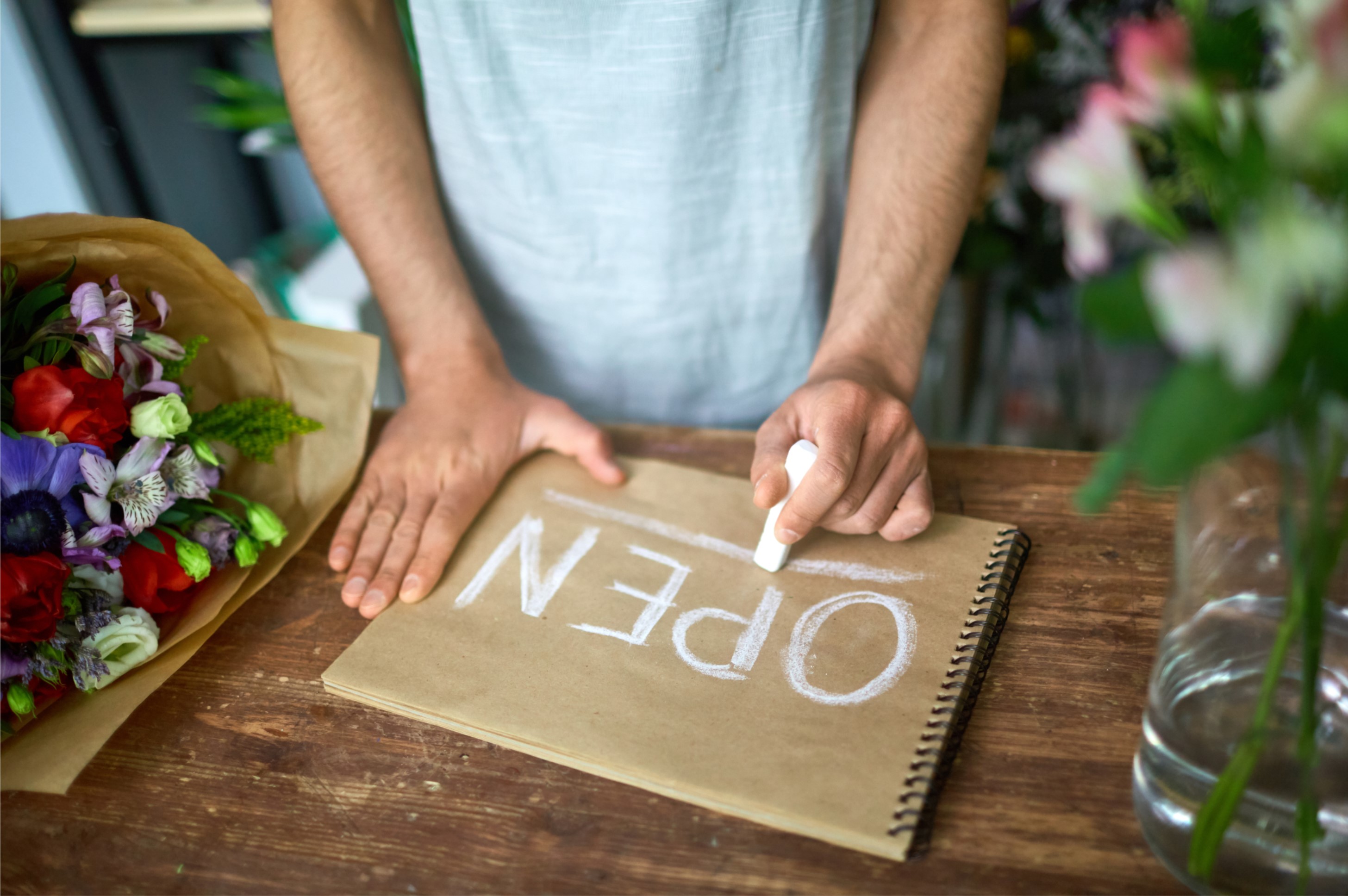 man writing open on sign for store