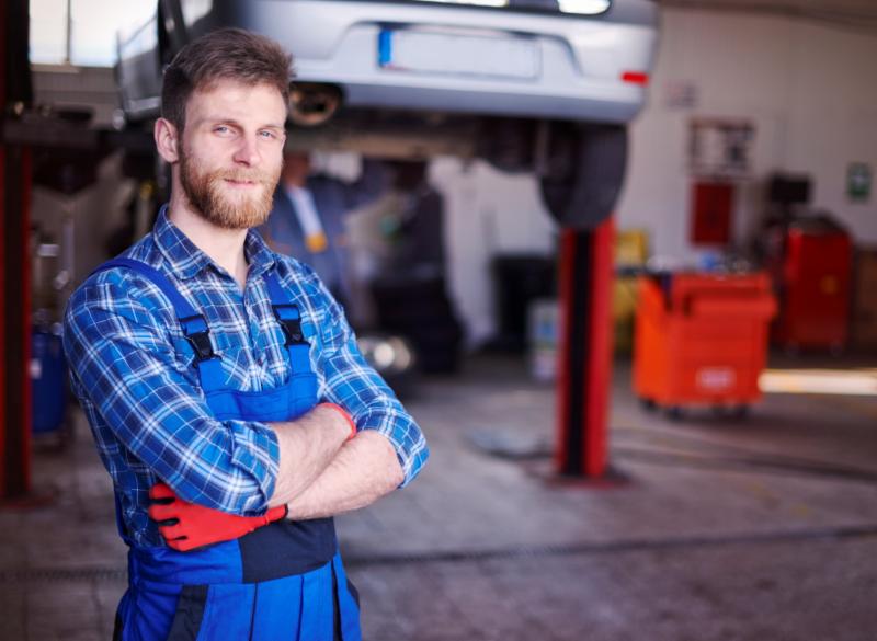 mechanic standing in shop in front of cars
